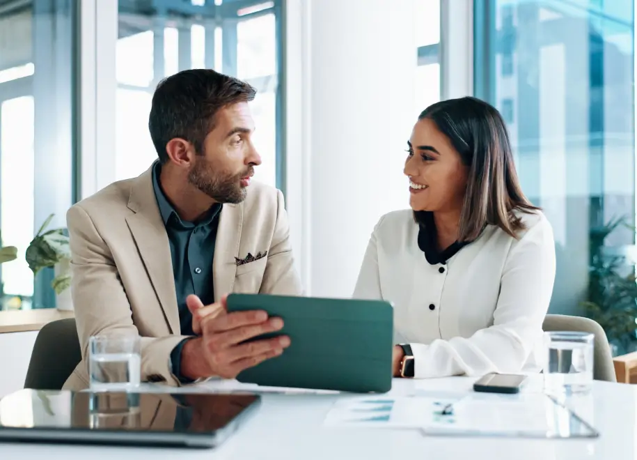 Two colleagues discussing work at table.